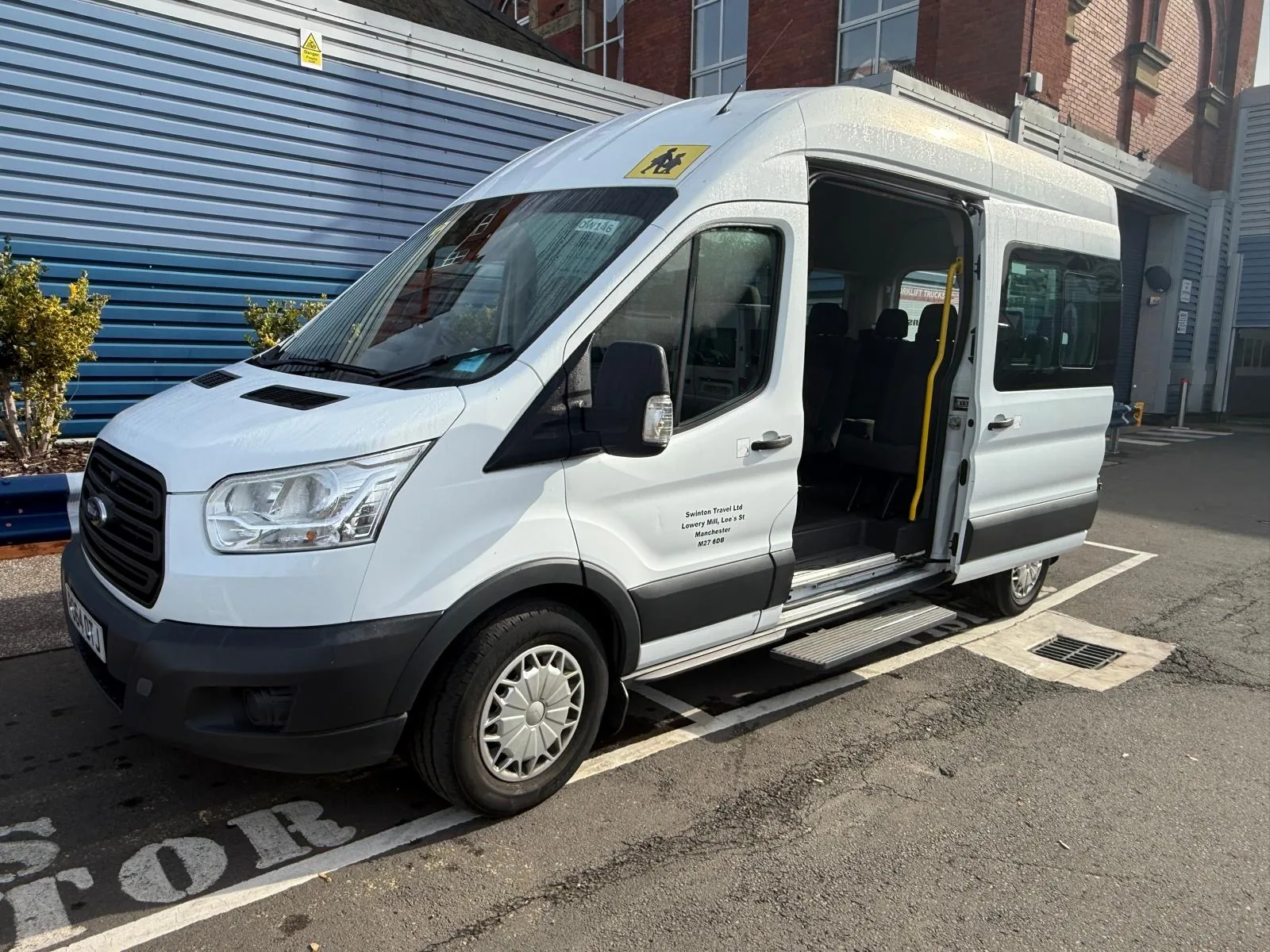 White 14 seater Ford Transit minibus with its sliding side door open, showing the step and passenger seats