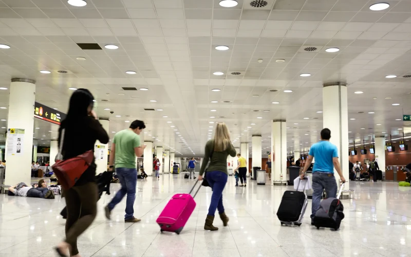 Travellers pulling their suitcases through a bright airport terminal