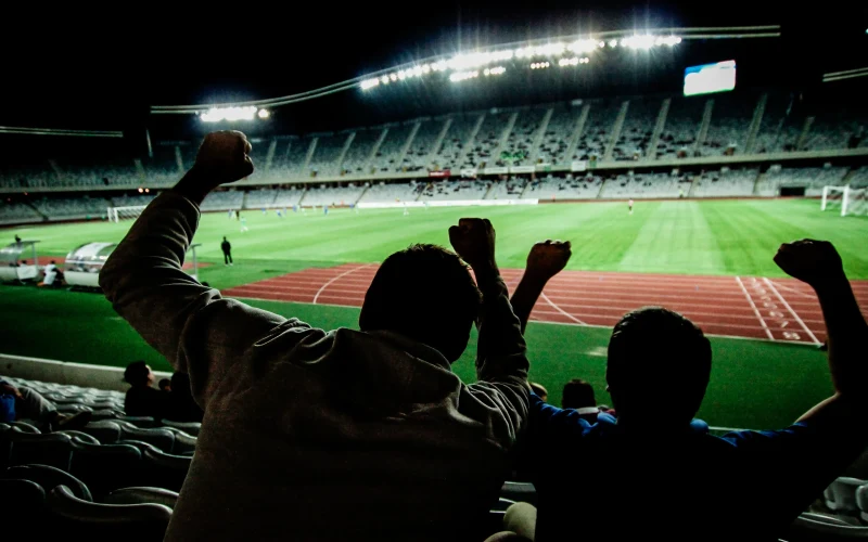 Football fans cheering in a floodlit stadium at night