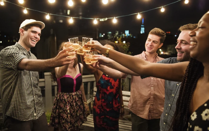 Group of friends toasting with drinks under festoon lights on a night out