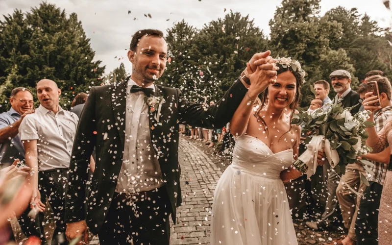 Newlyweds walking through a shower of confetti with their wedding guests either side